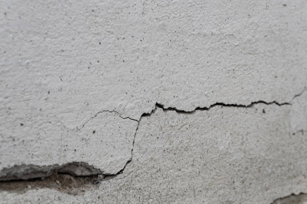 istock Old foundation and plaster wall with cracks. Building requiring repair closeup. 1211414618