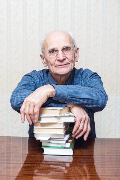 istock man with glasses folded his hands on stack of books 1211415177