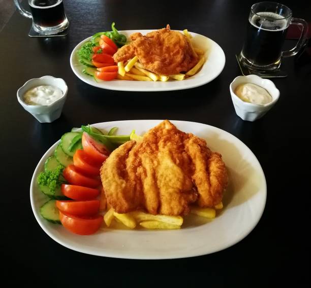 schnitzels aux frites, tartare souce et légumes, sur un plat en porcelaine blanche, repas pour deux personnes - cutlet schnitzel french fries scaloppini photos et images de collection