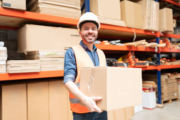 istock Smiling Male Employee Carrying Box At Warehouse 1211419280