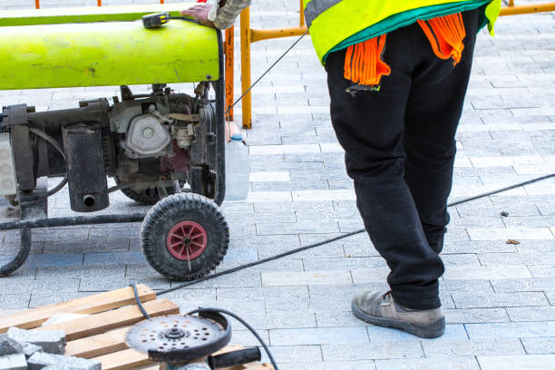 istock Construction work on pavement. Installation of concrete paver blocks on the sidewalk. The worker starts the petrol engine of electric power generator. 1211425164