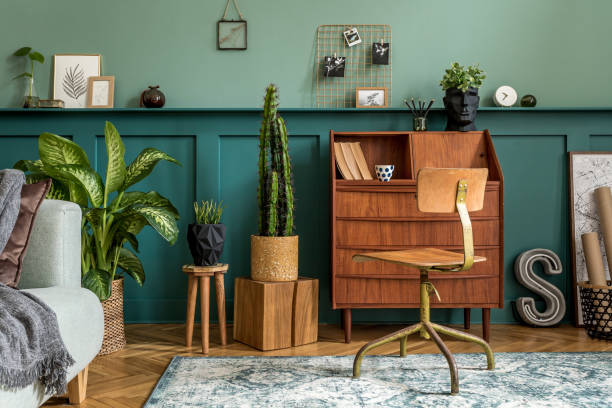 istock Stylish interior design with retro wooden cabinet, chair, elegant sofa, plants, cube, stool, decoratnion, poster and personal accessories. Modern retro concept of home office space. Template. 1211425399