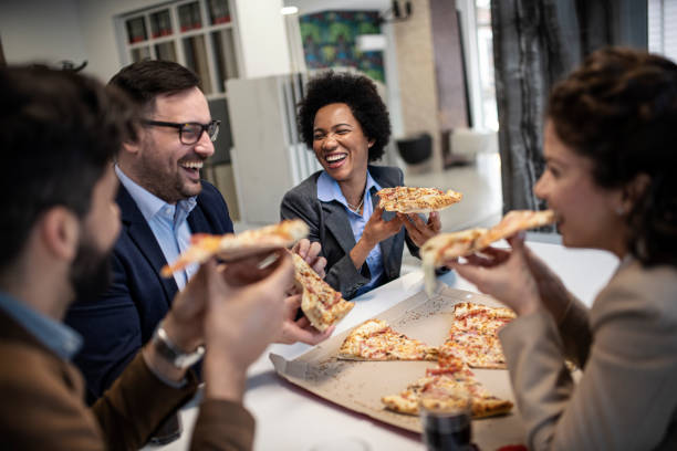 istock Positive business team eating pizza in office 1211427203