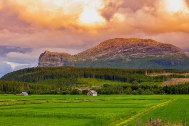 Dramatic red cloudy sunset over rocky mountain and green meadow