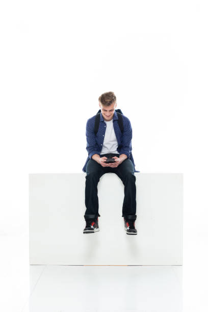 istock Caucasian boys resting in front of white background wearing button down shirt and using mobile phone 1211431312