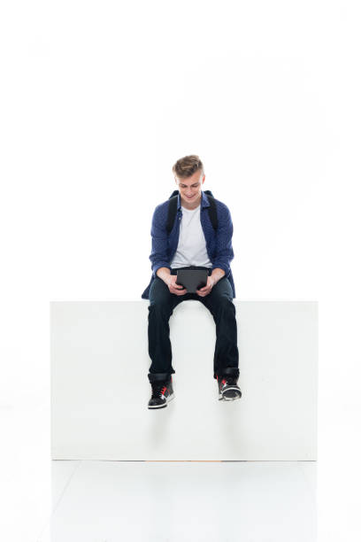 istock Caucasian boys resting in front of white background wearing shirt and using touch screen 1211431333