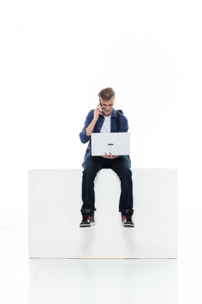istock Caucasian boys resting in front of white background wearing t-shirt and using computer 1211431402