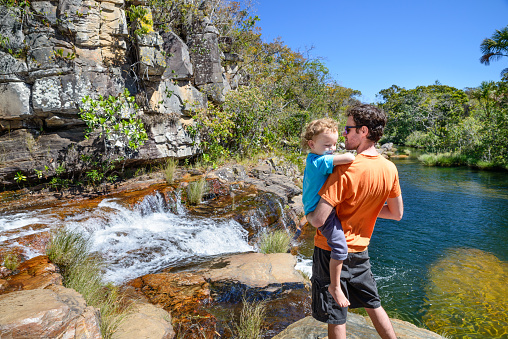 Family hikers on a waterfall, barefeet, enjoying the nature, river and water on a sunny day in Goiás, Brazil. Chapada dos Veadeiros.