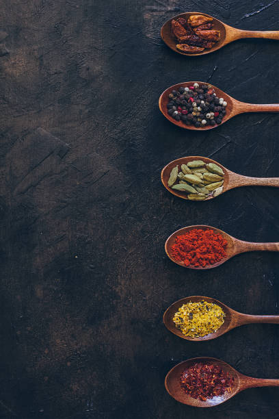 Colorful various spices in wooden spoons on old dark background. Top view with free space