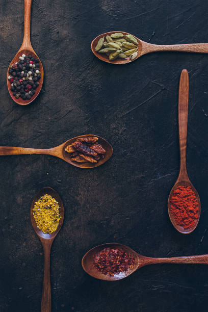 Colorful various spices in wooden spoons on old dark background. Top view with free space