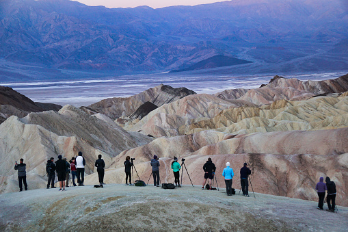 A line of photographers and their tripods waiting for sunrise at Zabriskie Point in Death Valley