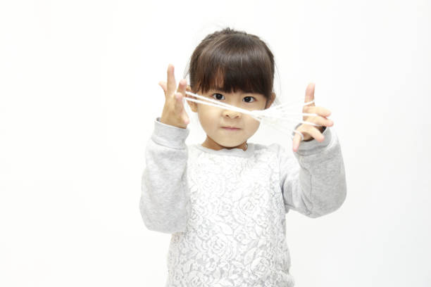Japanese girl playing with cat's cradle (white back) (5 years old)