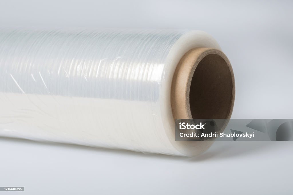 A roll of a clear polyethylene sheeting for packing. A close-up. Roll of wrapping plastic stretch film on white background with clipping path Foil - Material Stock Photo