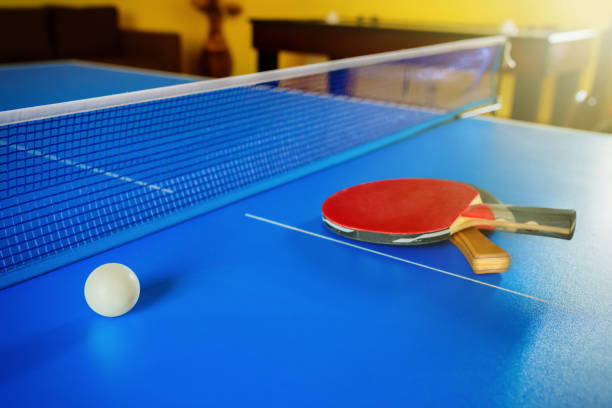 две ракетки для настольного тенниса или пинг-понга и мяч на синем столе. - table tennis table стоковые фото и изображения