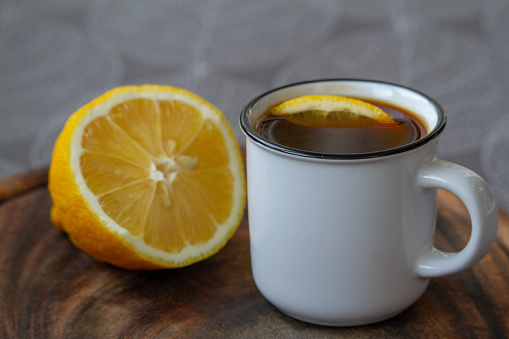 Cup of black coffee with a slice of lemon on a grey tablecloth, selective focus