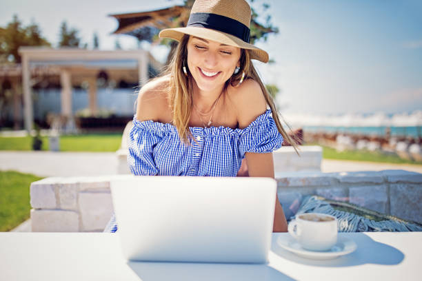 istock Young woman is working and drinking coffee on the beach 1211445373