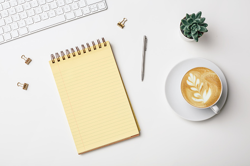 Top view of business desk table with tropical leaves and mock up accessories on white background.flat lay design. stock photo