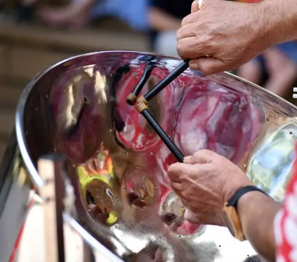 Musicians hands are skillfully performing calypso music with a Jamaican steel drum