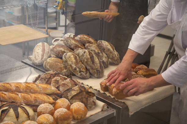istock Baker in a bakery with bread and oven in the background. Industry 1211449985
