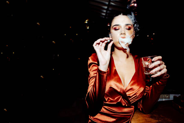 Portrait of a woman with the cigar Portrait of a attractive young woman smoking a cigar and holding a glass of whiskey in the bar smoking women luxury cigar stock pictures, royalty-free photos & images