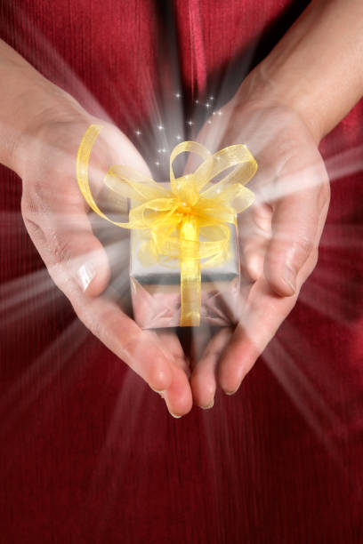 woman holding glowing gift box in palm of her hands Close up young adult woman showing glowing gift box in palm of her hands perfect gift stock pictures, royalty-free photos & images