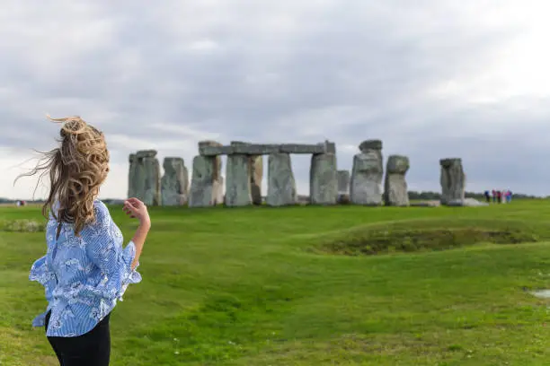 Beautiful girl with windy hair standing and looking at Stonehenge.