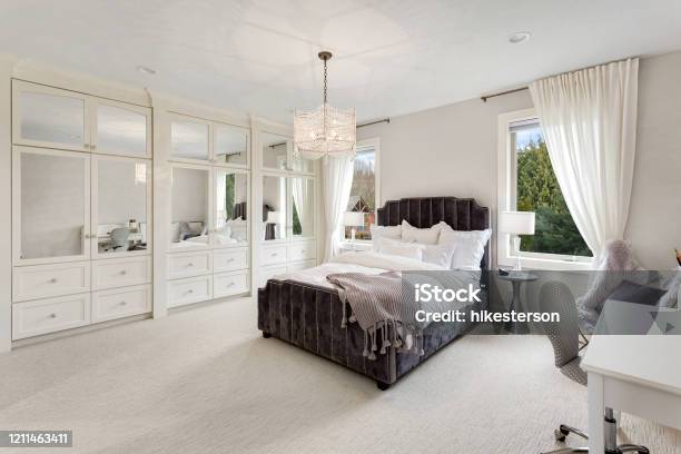 Master Bedroom In New Luxury Home With Large Windows Chandelier Carpet And Elegant Decor Stock Photo - Download Image Now