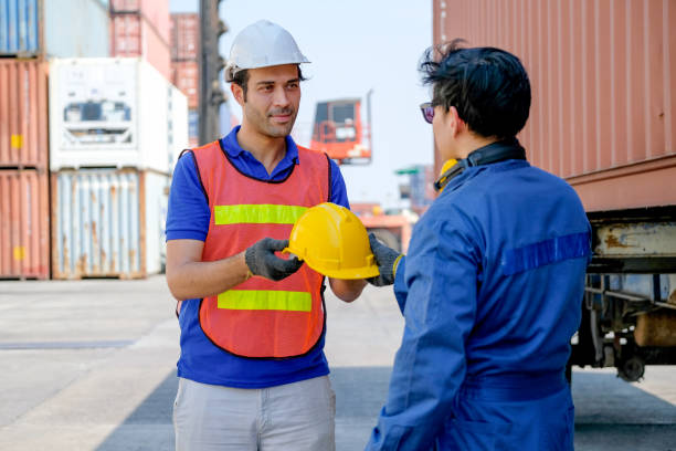 istock Technician or worker give safety helmet to his co-worker in cargo container shipping area 1211464457