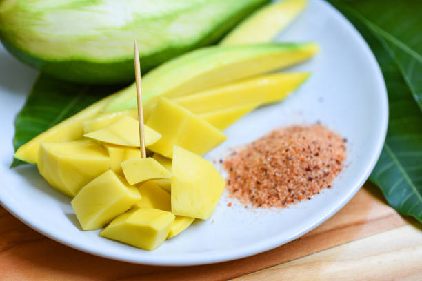 Mango slice on white plate and leaves from tree tropical summer fruit concept / Ripe mango pickled fruit and green mangoes for snack