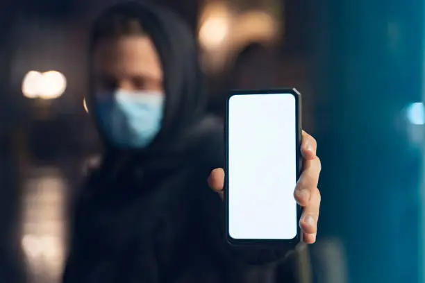 Man with hygiene mask holding empty screen smartphone, coronavirus/airpollution