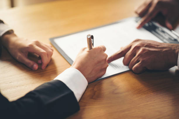 The hand of a business man is using the index finger to let the customer sign the contract, contract, business agreement. stock photo