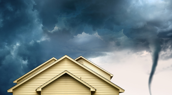 close up rooftop of a wooden house over stormy clouds sky and approaching tornado.