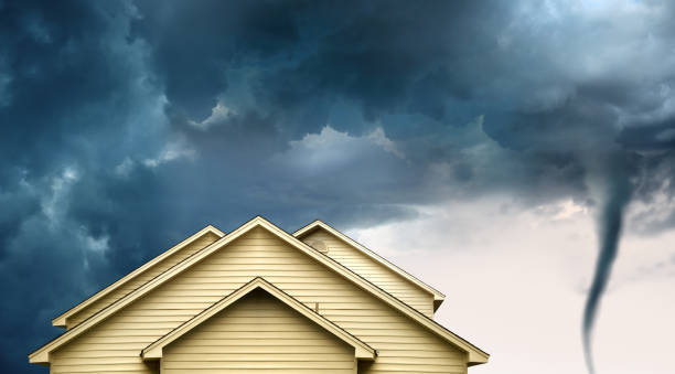 home insurance concept of house and tornado close up rooftop of a wooden house over stormy clouds sky and approaching tornado. tropical storm photos stock pictures, royalty-free photos & images
