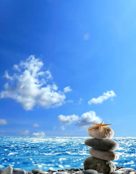 White sandy beach with stacked balancing rocks and sea shells. Creating balance in one’s life with patience, thanks and grace. Spiritual rituals.