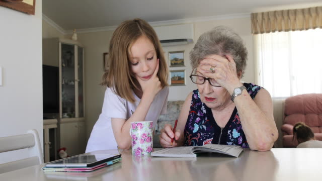 Grandmother and granddaughter doing crossword puzzle together