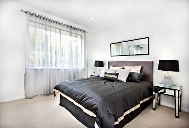 istock Modern bedroom with black decoration and mirror beside lamps 1211485785