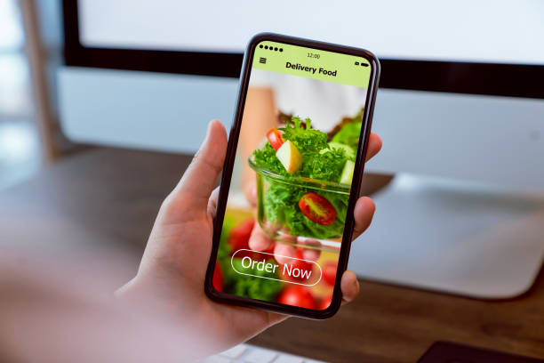 istock Woman using smartphone and touching application screen for ordering salad online on the table at office. 1211487756