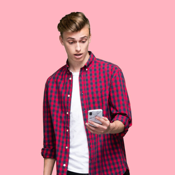 kaukaski młody mężczyzna stojący przed kolorowym tłem ubrany w t-shirt i za pomocą inteligentnego telefonu - men on the phone square waist up zdjęcia i obrazy z banku zdjęć