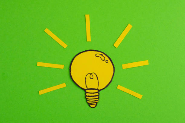 istock Composition with cut out paper, drawing light bulbs on a green background. Creative concept symbolizing the idea 1211490138