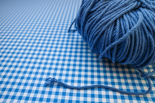 Blue skein of knitting yarn on a blue checkered background.