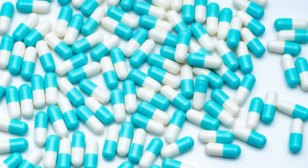 白い背景に青と白のカプセルの丸薬.製薬業界。青いパステルカラーカプセルの丸薬は、白いテーブルに広がった。薬剤師の背景。ヘルスケアと医療。薬局製品。 - amoxicillin ストックフォトと画像