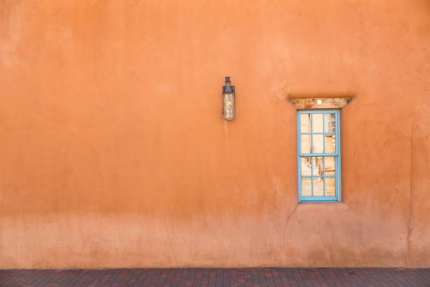 Orange adobe wall with blue window and lantern in Santa Fe, New Mexico