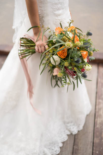 istock Bride in white gown hand holding flower bouquet 1211494434