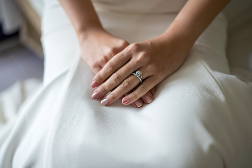 Bride dressed in white wedding gown and hand with wedding rings