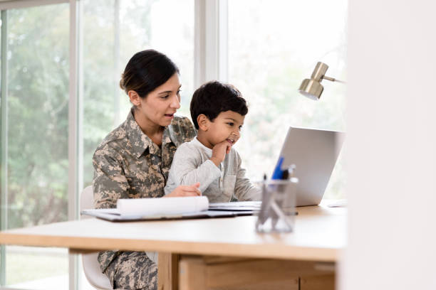 istock Soldier mom takes break from work; uses laptop with son 1211494782