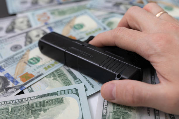 main tenant une arme à feu se trouve sur un tas d’argent - gun handgun violence kidnapping photos et images de collection