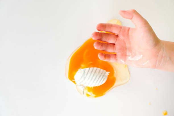 istock hand holding egg yolk and another hand smash egg 1211496746