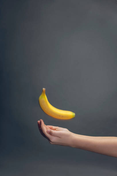 istock two empty children hands catching a banana on dark background with copy space 1211501932