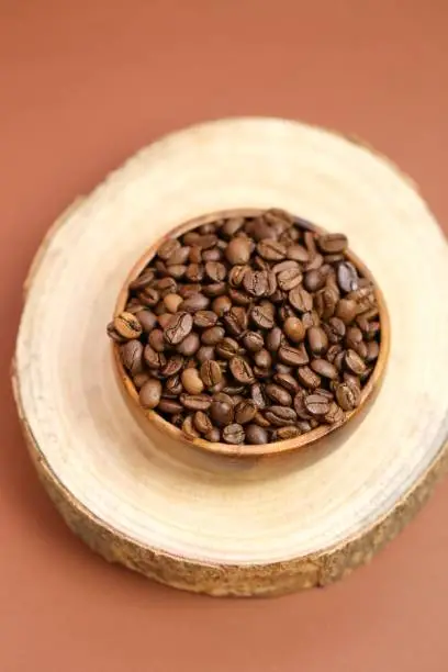 coffee beans in a round cup on a cut of a tree on a dark brown background.Coffee drink.Coffee beans in a minimalist style.top view