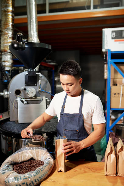 istock Man putting roasted coffee in packages 1211504272